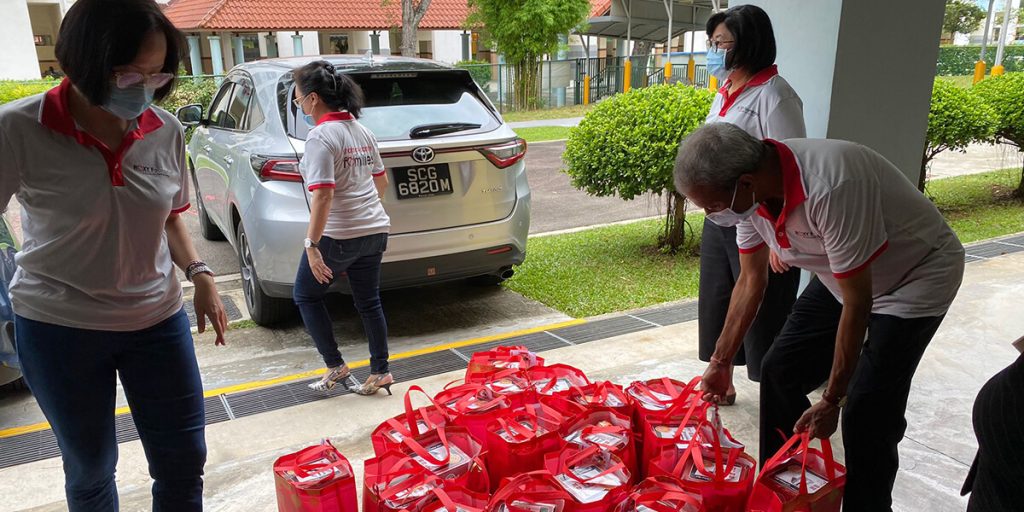 Team members arranging red bags for distribution in a residential area